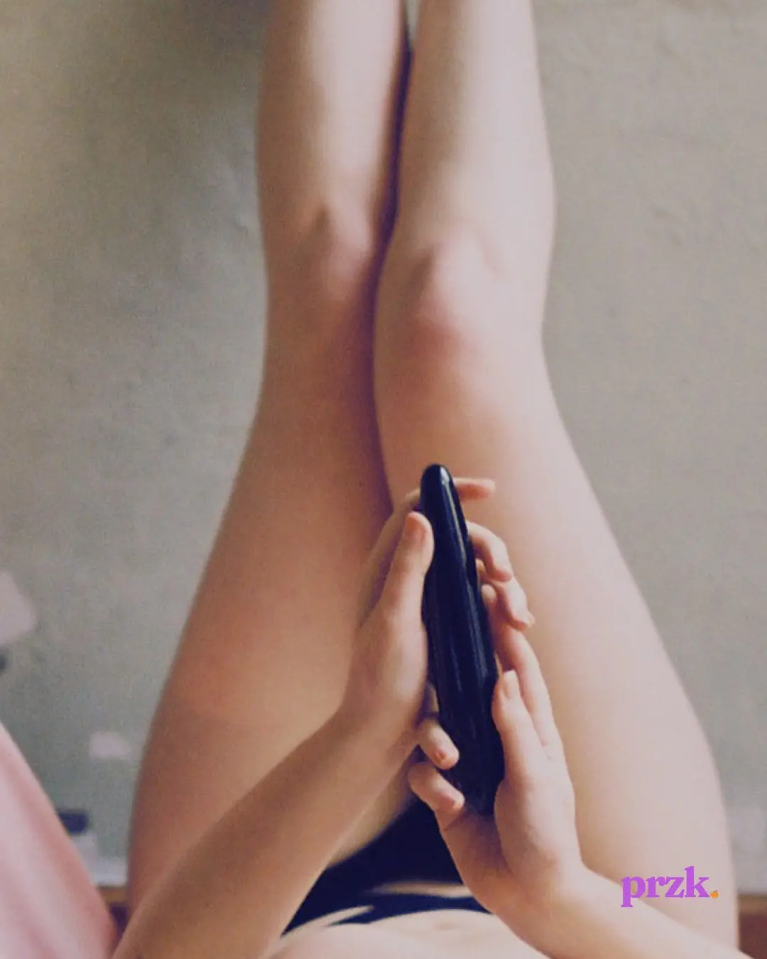 Legs against a wall, hands held in prayer around a vibrator